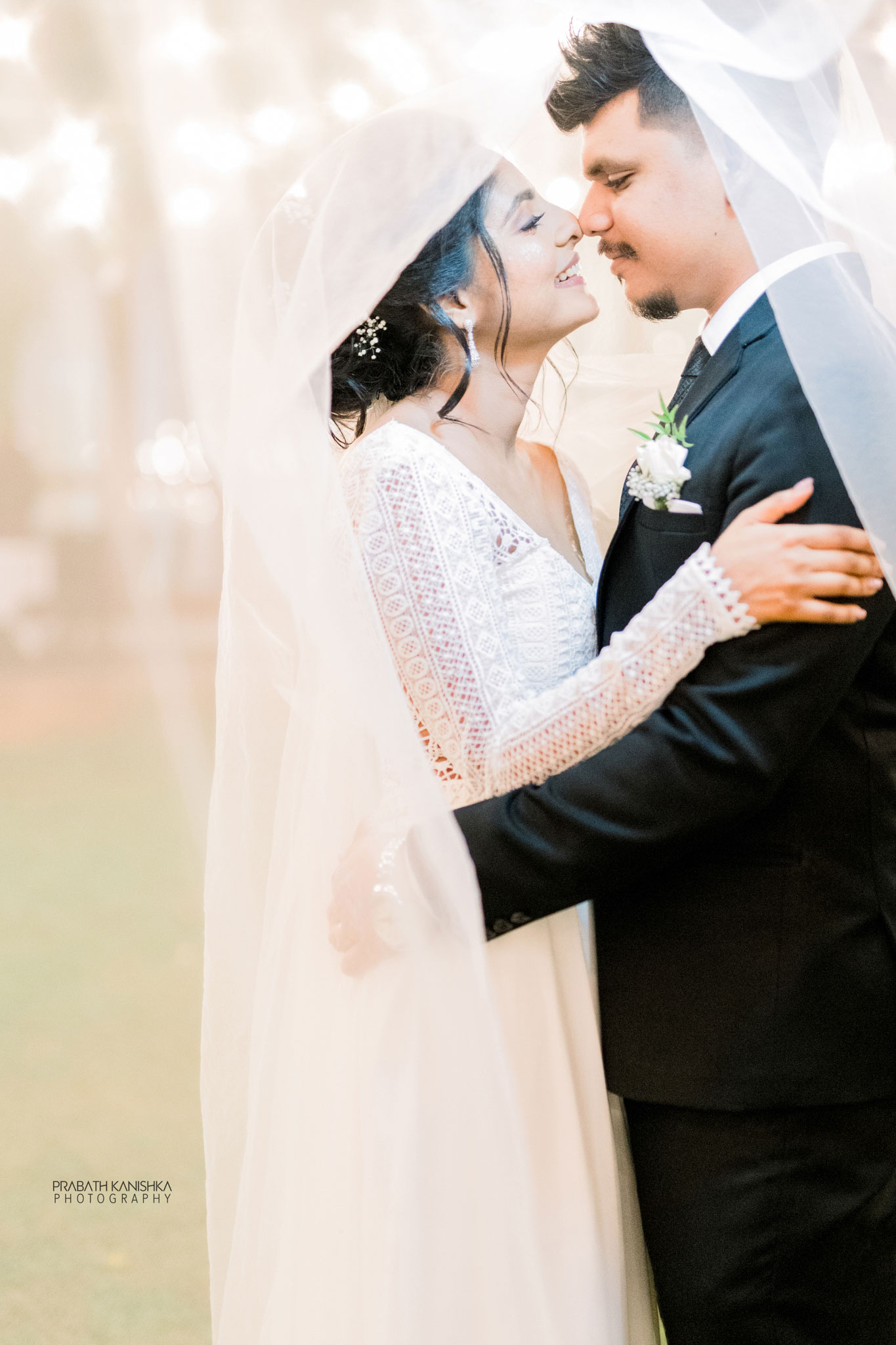 Sri Lankan bride and groom beneath a veil at golden hour